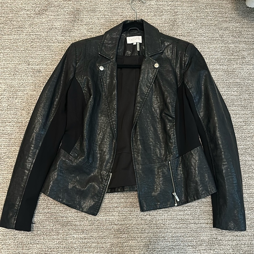 Women’s black faux leather jacket with silver zipper detailing and peplum back